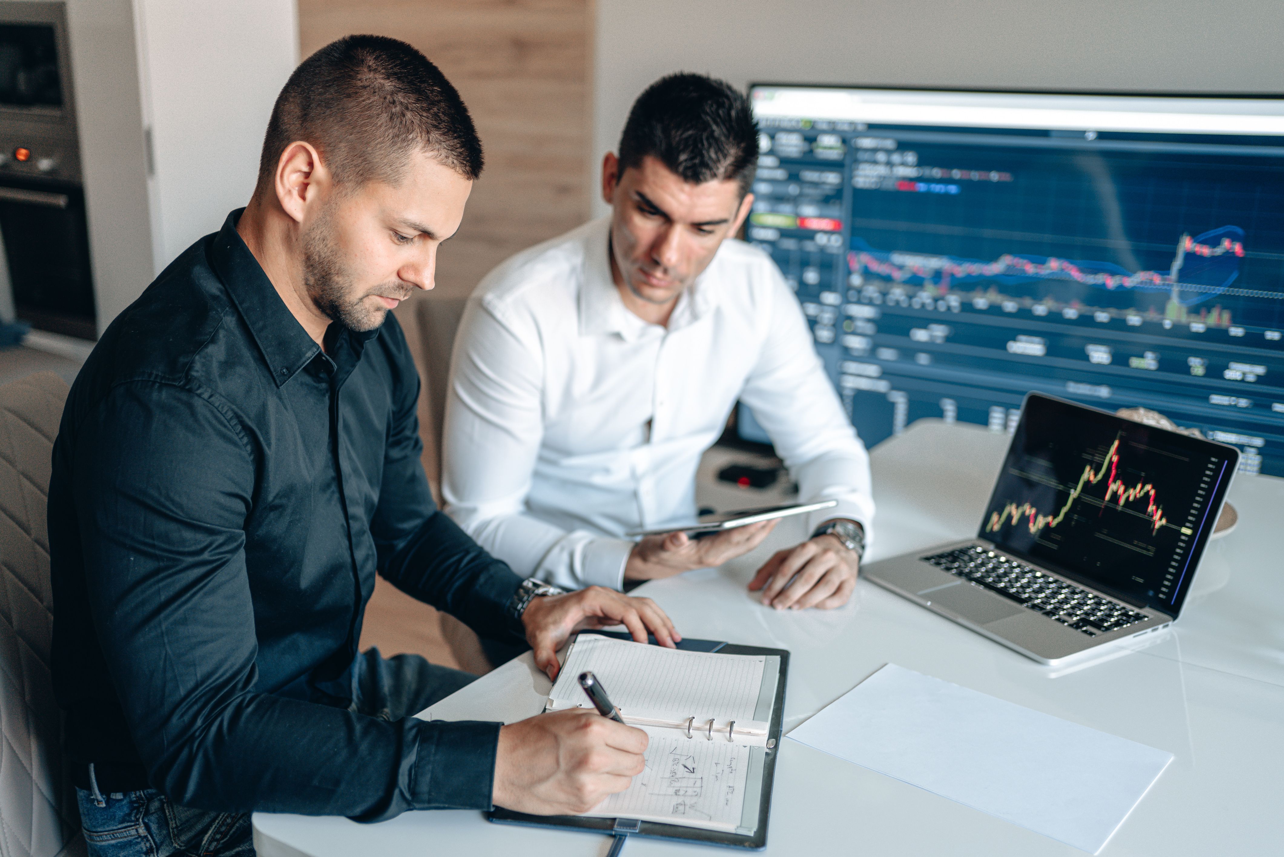 Business professionals examine financial data and charts together in an office.